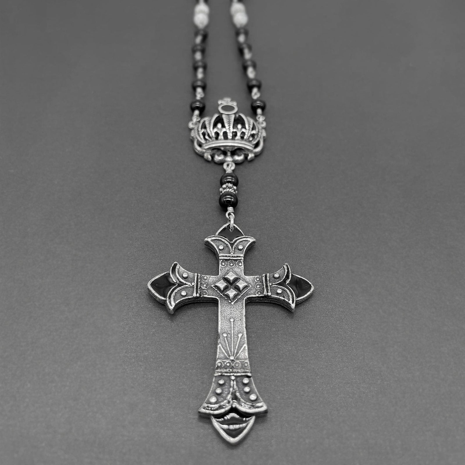 Close up of silver cross with black accents on the beaded rosary necklace
