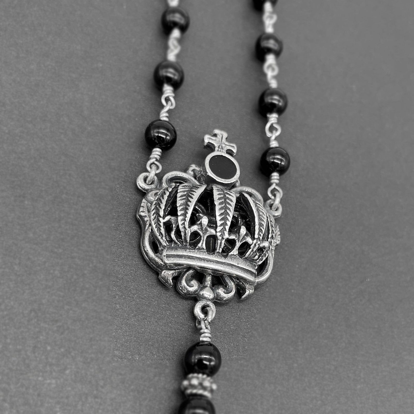 Detailed close up view of the dimensional cross connector on the rosary necklace for women