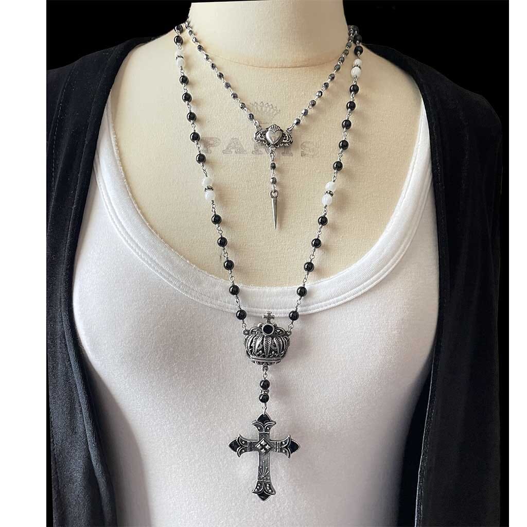 Showing the black beaded rosary necklace styled with a shorter necklace