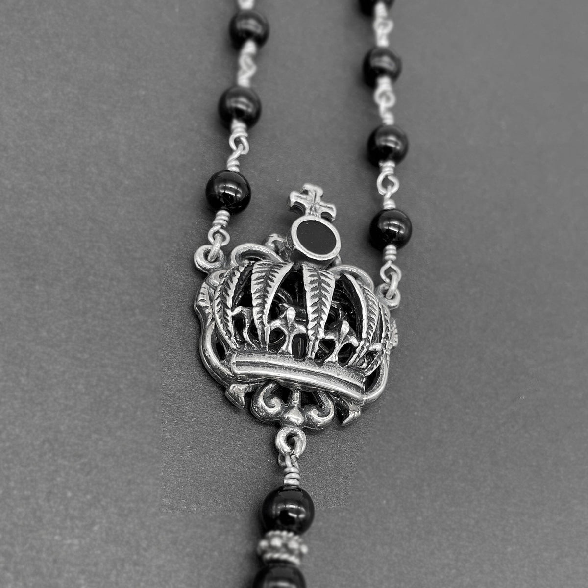 Detailed close up view of the dimensional cross connector on the rosary necklace for women