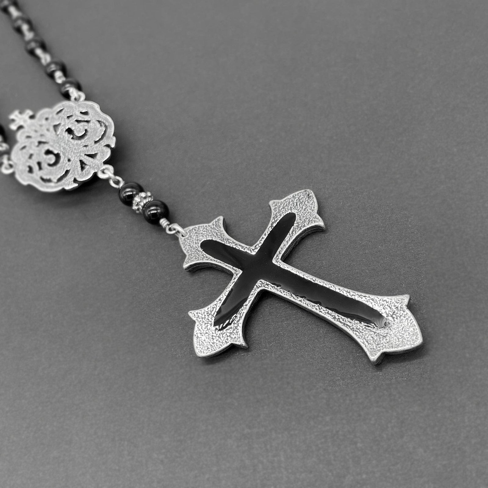 Close up view of the back of the silver cross on the black beaded rosary necklace